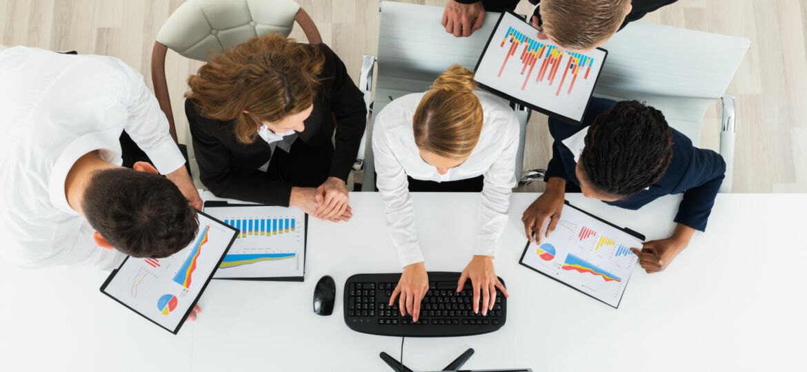 Group,Of,Multiracial,Businesspeople,Working,On,Graphs,In,Office